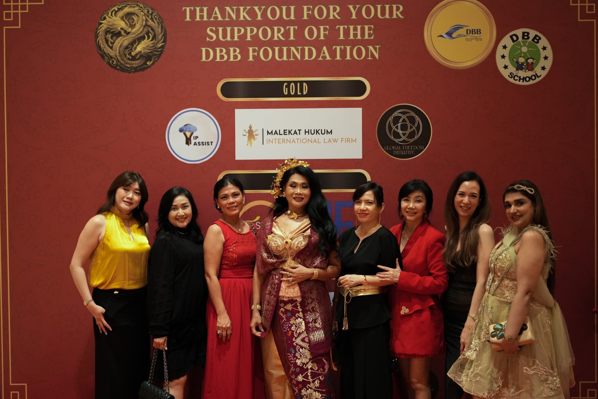 Guests posing at an evening gala, one in traditional Balinese attire
